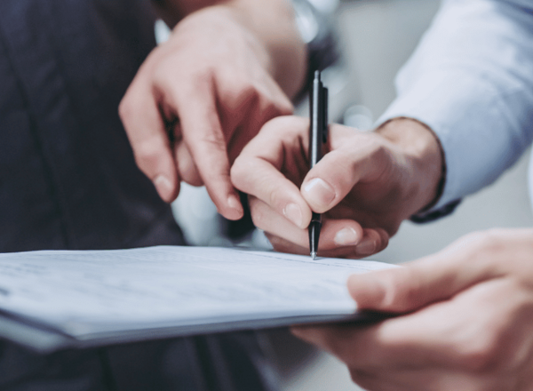 Zwei Personen füllen gemeinsam ein Formular auf einem Klemmbrett aus