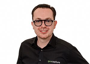 Porträt eines Mannes mit Brille im schwarzen Hemd mit geocapture-Logo vor weißem Hintergrund
