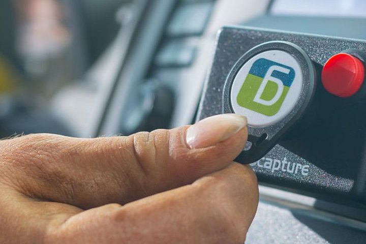 Hand hält geoCapture RFID-Schlüssel an ein Fahrzeugterminal zur Fahreridentifikation und digitalen Fahrzeugfreigabe.