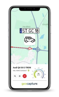 Smartphone zeigt eine geoCapture-App mit Fahrzeug-Tracking. Auf der Karte ist ein Auto mit dem Kennzeichen „ST GC 18“ zu sehen, das sich auf einer Straße in der Nähe eines Autobahnkreuzes bewegt. Unten sind Fahrtdetails wie Modell „Audi Q4 50 E-TRON“ und aktuelle Geschwindigkeit angezeigt